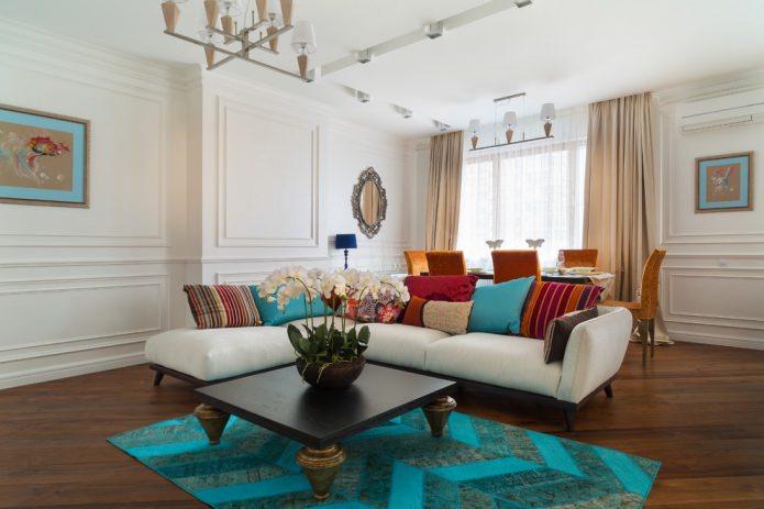 Wohnzimmer mit türkisfarbenem Teppich und Kissen