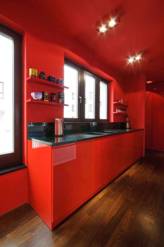 Ganz in Rot gehaltene Küche mit Holzboden