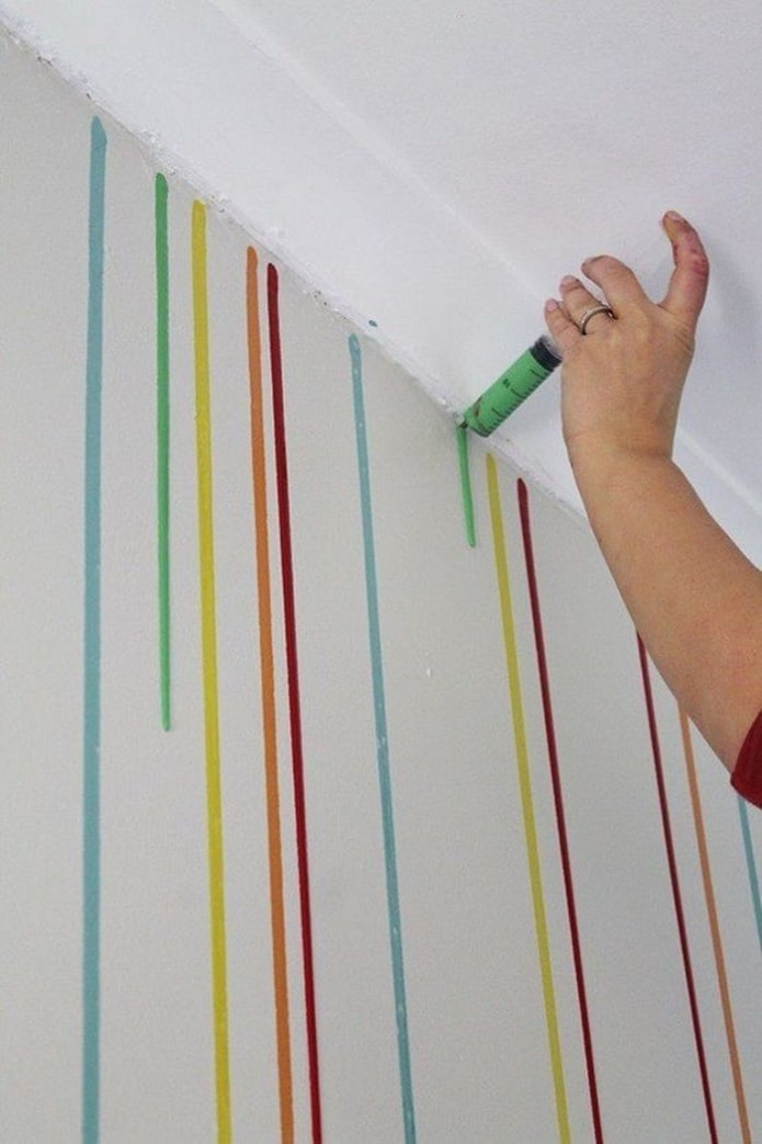 Farbtropfen werden mit einer Spritze auf die Wand aufgetragen