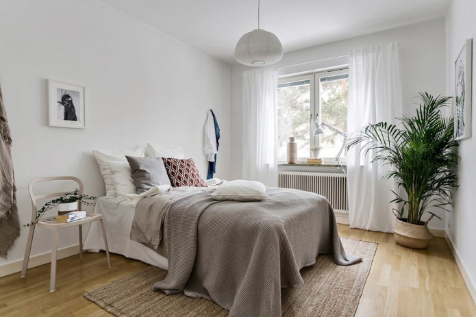 Bett mit grauer Tagesdecke im Schlafzimmer