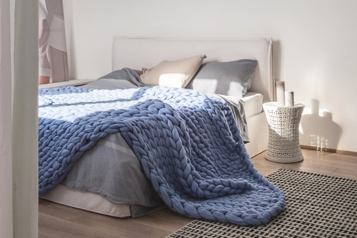 Bett mit einer großen Stricktagesdecke im Schlafzimmer