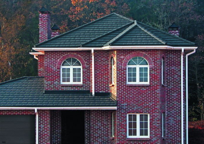 ein Haus aus dunkelrotem Backstein mit schwarzem Dach
