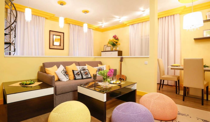 Hellgelbes Wohnzimmer mit bunten Kissen und gestrickten Poufs